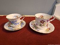 Two Paragon teacups with saucers, showing floral designs and gold trim
