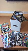 White short box filled with comics plus about 15 issues spread on table
