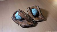 Two leather baseball gloves each holding a baseball