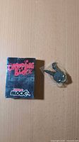 Front of sealed Chopping Block box and bagged enamel pin