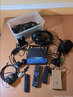 Overview of lot showing router, headsets, remotes, power bank, mouse and bin of cables