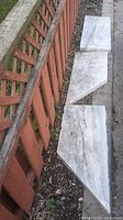 Three marble slabs laid along fence showing size and angled cuts