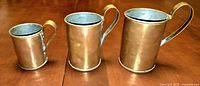 Front view of three copper steins in graduated sizes