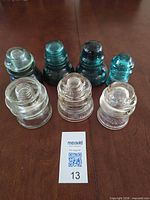 Seven glass insulators displayed; three clear front, four green rear