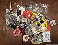 Pile view showing mix of keychains, bottle opener, wooden disc, smiley face, Strongbow bags