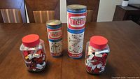 Two Tinkertoy cans and two Lego jars on table