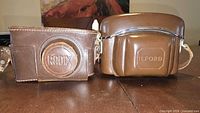 Both brown leather fitted camera cases, Radix and Ilford branding visible