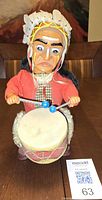 Front view showing entire drummer toy holding drumsticks and drum