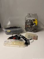 Overview of lot showing container of black screws, jar of mixed hardware, glue gun with glue sticks, small organizer