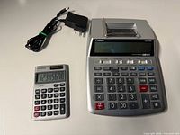 Canon P23-DHV printing calculator with AC adapter and Casio SL-300SV handheld calculator displayed powered on