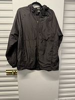 Front view of black hooded windbreaker on hanger