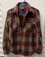 Full view of plaid flannel shirt on hanger