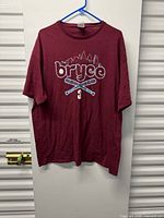 Full view of maroon graphic T-shirt hung on hanger