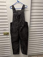 Full view of black insulated bib ski pants on hanger