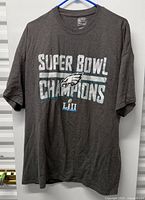 Full front view of grey Eagles Super Bowl Champions T-shirt on hanger