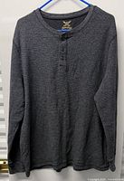 Full front view of dark grey henley sweater on hanger