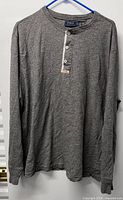 Full view of grey long sleeve henley shirt on hanger