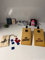 overall view of all items including cornhole boards, bean bags, plush, bath bombs, cards, frog
