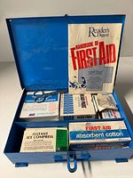 Open kit showing booklet, scissors, adhesive strips, bandages, ice compress, cotton