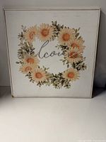 Front view of square welcome wall art showing floral wreath and script.