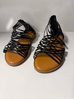 top view of both sandals showing black criss-cross straps and tan footbeds