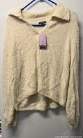 Front view of Wild Fable cream fuzzy sweater on hanger showing collar, v-neck, high-low hem, tag attached