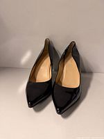 Front view of the pumps showing pointed toes and patent finish