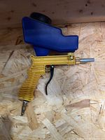 Left side view showing yellow grip, blue hopper, metal nozzle and air fitting