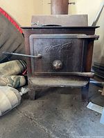 Front view of Harwood cast iron stove showing door logo, handle and legs