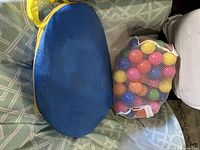 Folded blue fabric carry bag and mesh bag of play balls