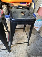 Side view of one stool showing black finish, metal construction, footrest