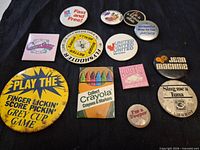 Front view of all 13 buttons showing slogans, colours and shapes