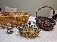 Rectangular wicker basket, round wicker basket, metal wire basket with grape-leaf accents, soda can for scale