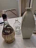 Group showing straw-wrapped bottle, skull bottle and green vase