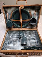 Basket open showing plates, mug, tumbler strapped to lid and glasses, cutlery in base