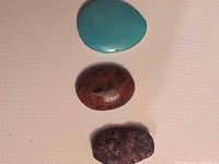 group of three cabochons arranged vertically: blue, red-brown, purple