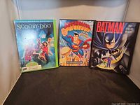 Front view of three DVD cases: Scooby-Doo, Superman, Batman