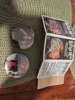 two pinback buttons and folded rules insert on placemat