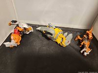 Three incomplete Transformers dinosaur figures on black surface