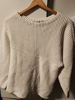 Front view of cream ribbed GUESS sweater on hanger