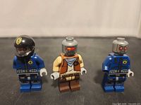 Front view of three robot-themed Lego minifigures standing side by side
