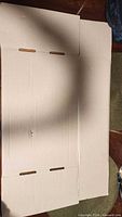 Flattened white corrugated cardboard box showing scoring and flaps