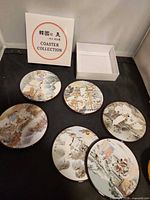Set of six round ceramic coasters with illustrated Korean scenes and white presentation box