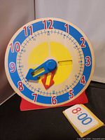 Front view of wooden teaching clock with time cards beside