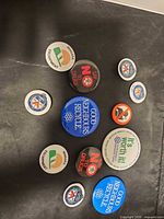 Overview of all eleven pins laid out on dark surface