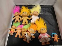 Group of all nine troll dolls displayed on black surface
