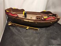 Angled view of brown Simba toy boat hull with decal and loose accessory piece