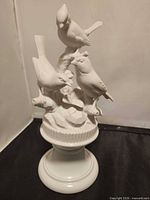 front view of white ceramic bird trio figurine on pedestal