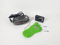 Canon camera, Durabrand clock radio, green foot-shaped calculator overview