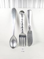 Front view of spoon, fork and knife standing upright